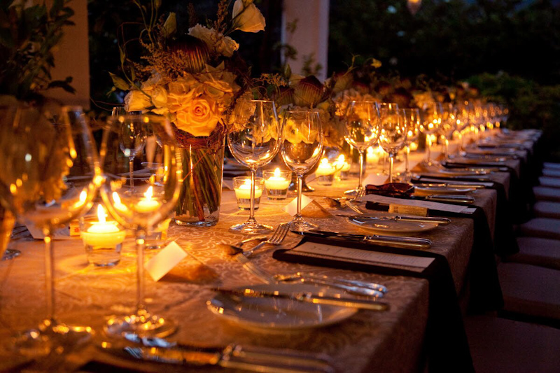 Beautiful reception table setting with centerpieces of roses and warm candlelight - photo by South Africa based wedding photographer Greg Lumley